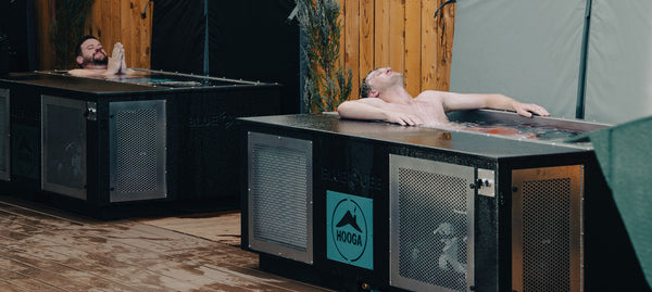 Two men in two cold plunge tubs placed side by side at a wellness center. 