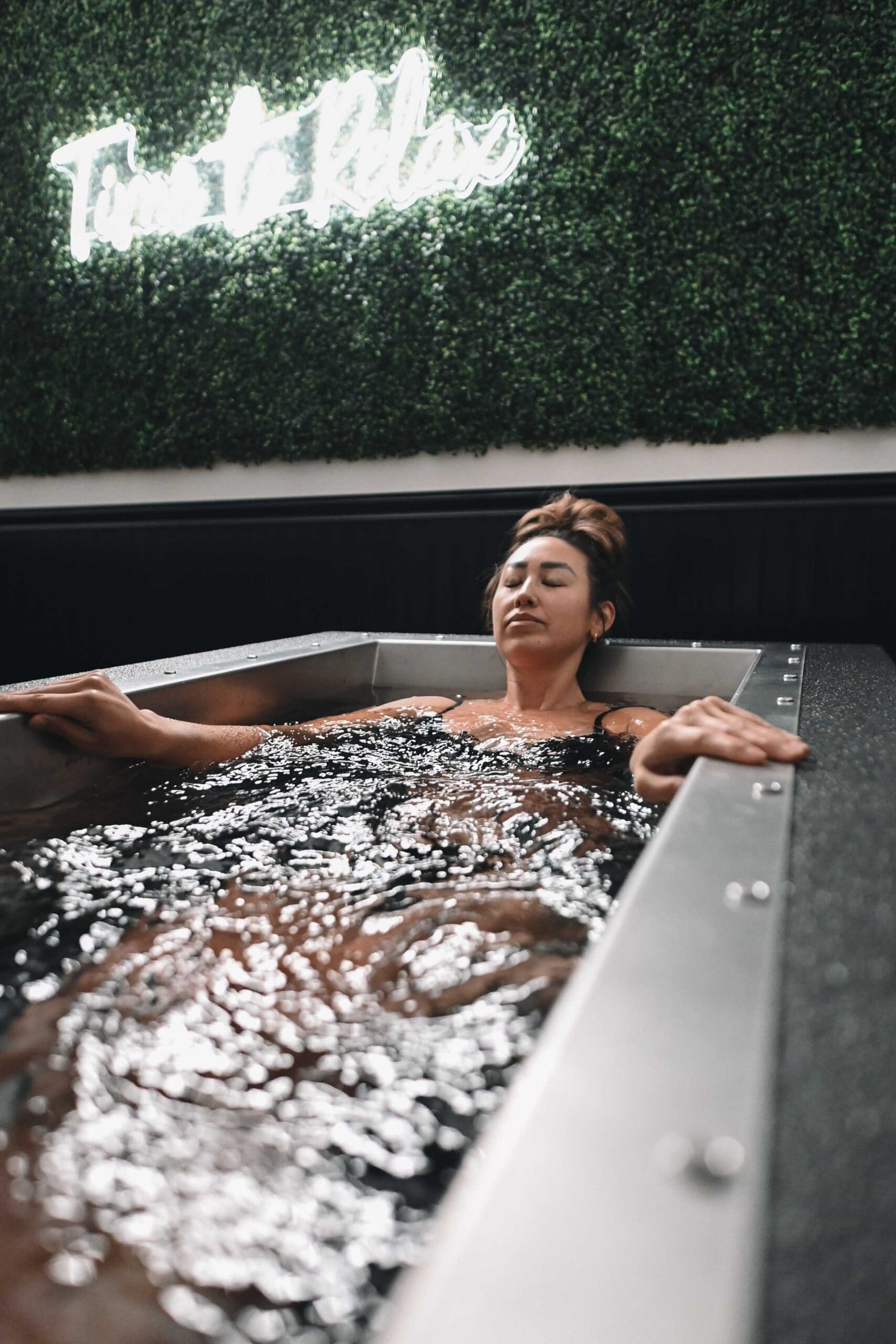 Client fully immersed in a BlueCube C2 black cold plunge at Fire Ice and Moore in Southern Pines, NC