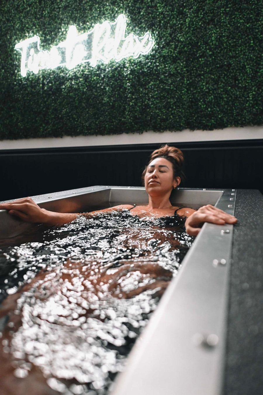 Client fully immersed in a BlueCube C2 black cold plunge at Fire Ice and Moore in Southern Pines, NC