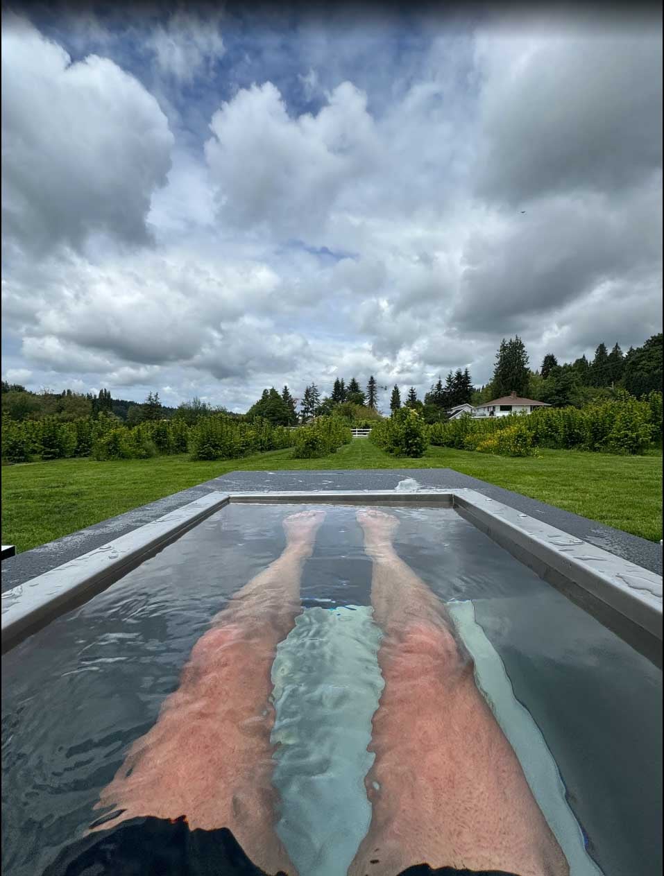 Open-air leg soak in a BlueCube C2 black cold plunge overlooking the pasture at Fyre Sauna in Redmond, WA