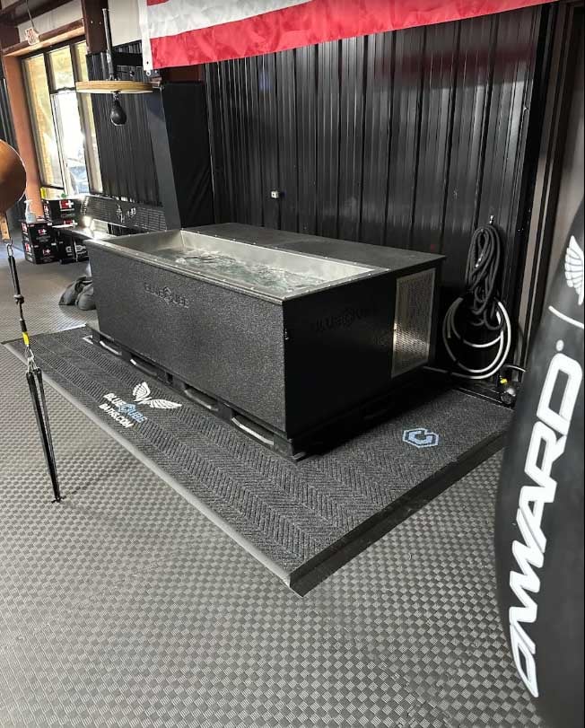 BlueCube C3 black cold plunge in the Team Onward training gym with co-branded heavy bag visible at right