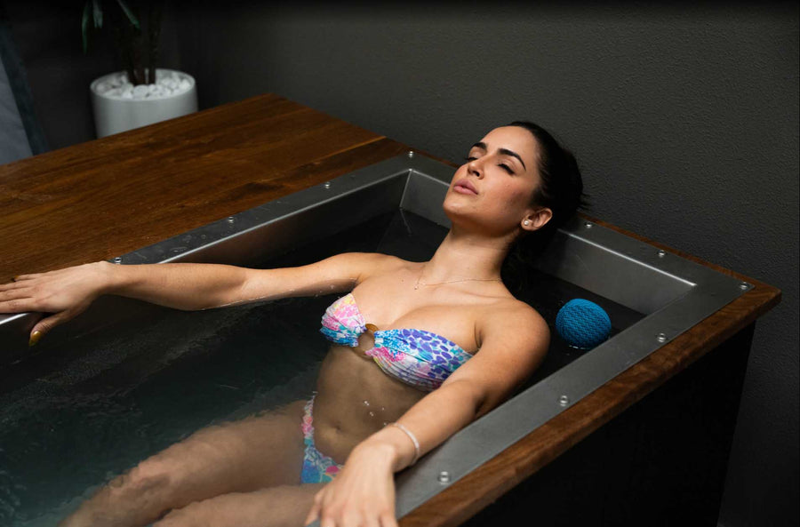 Woman fully immersed in a custom BlueCube C3 cold plunge with black walnut deck at Project Wellbeing in Las Vegas, NV