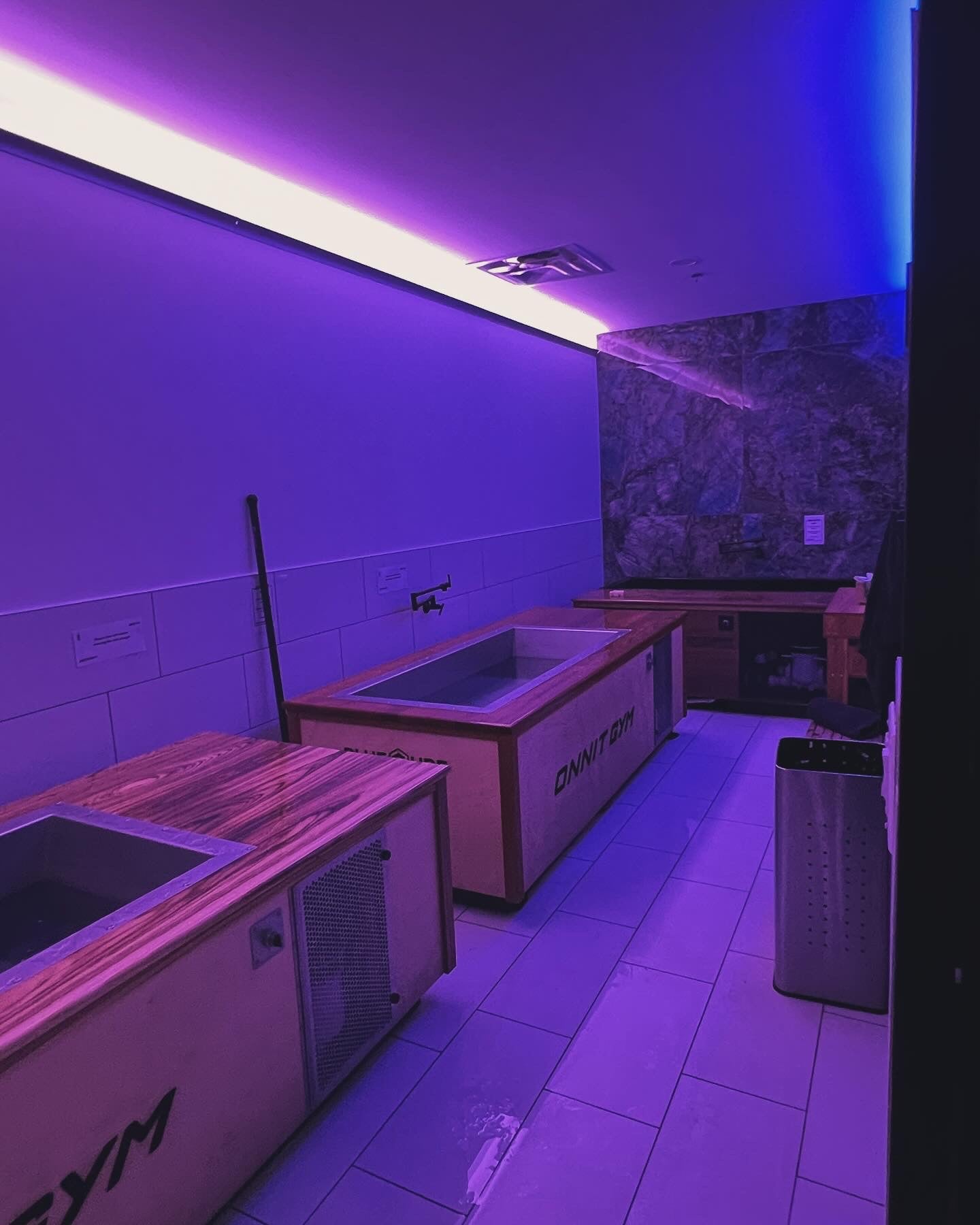 Recovery room with multiple BlueCube cold plunges and stone accent wall at Korrect Fitness in Austin, TX