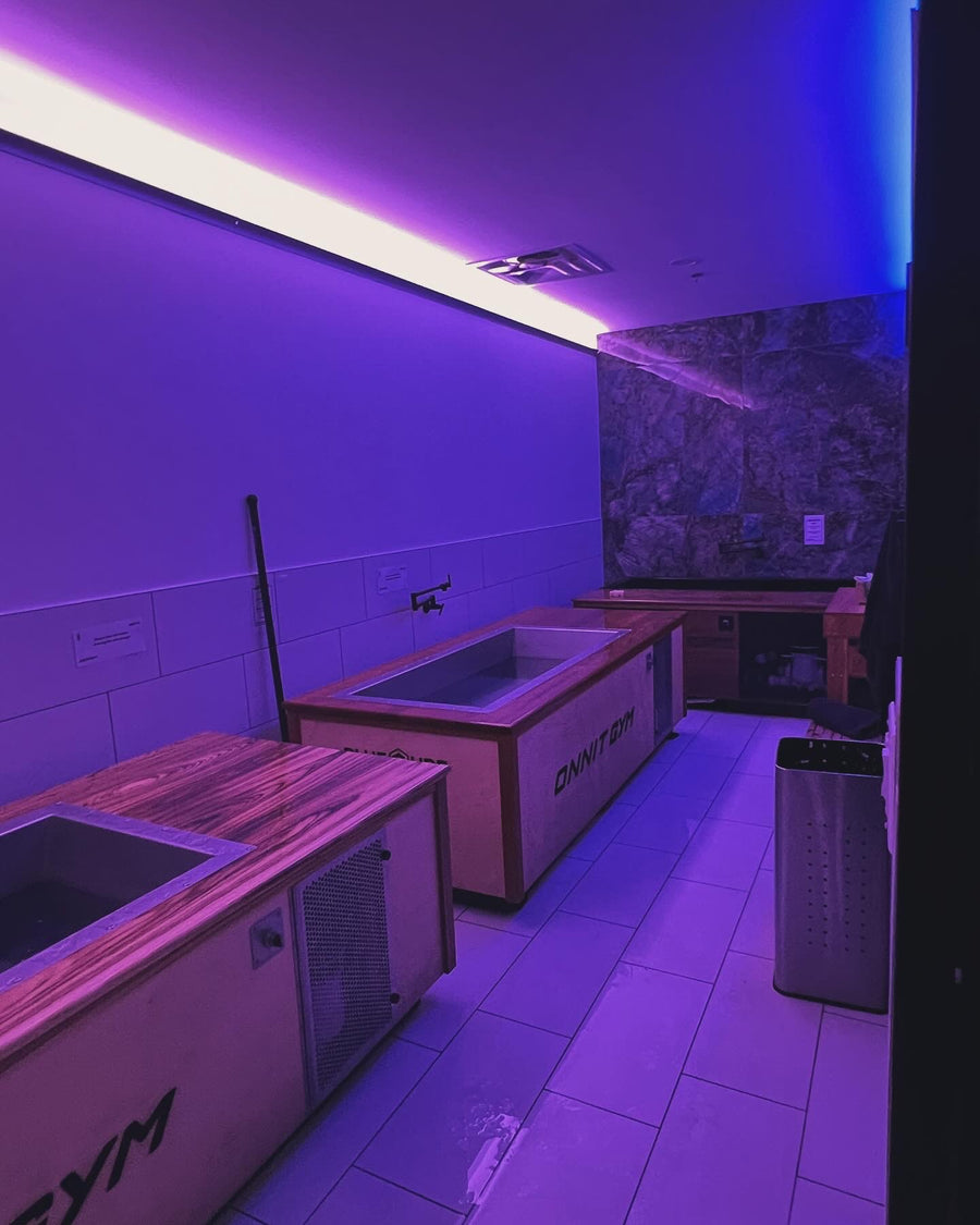 Recovery room with multiple BlueCube cold plunges and stone accent wall at Korrect Fitness in Austin, TX