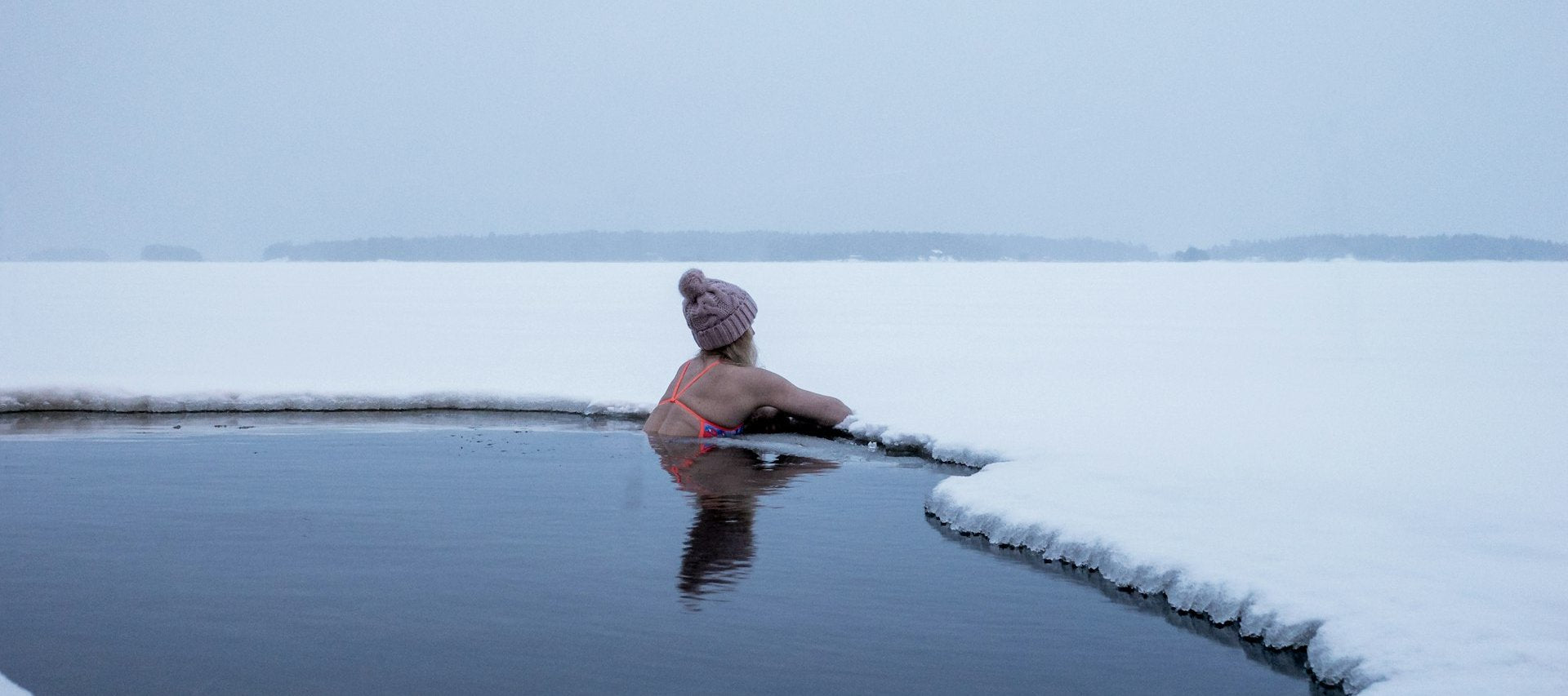 Woman resting calmly in a hole cut through sea ice