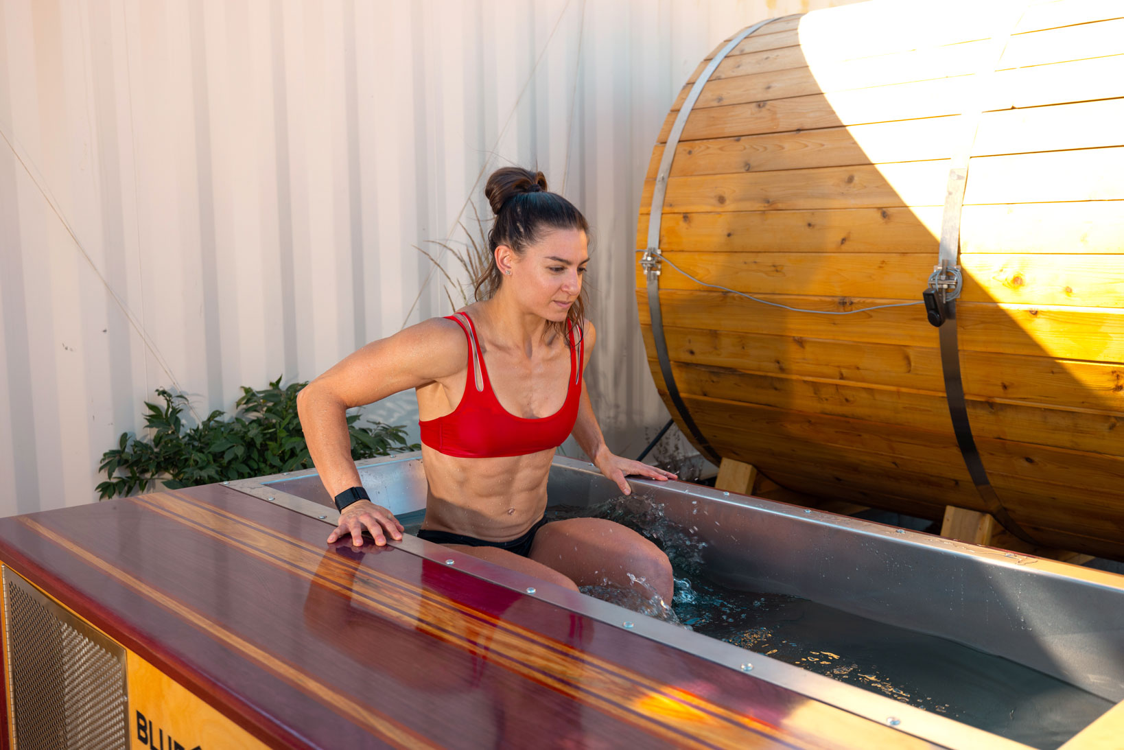 Woman cold plunging and keeping track of her time and temperature. 