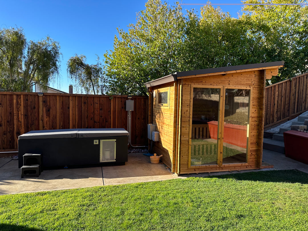 CoreChill³ Cold Plunge Tub next to a traditional sauna in a backyard. 