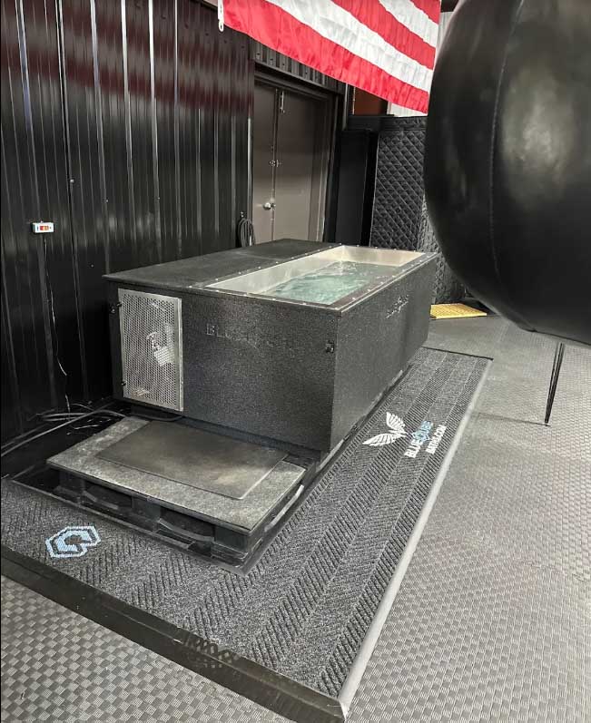 BlueCube C3 black cold plunge installed at the Team Onward private training gym, with heavy bag and American flag in frame